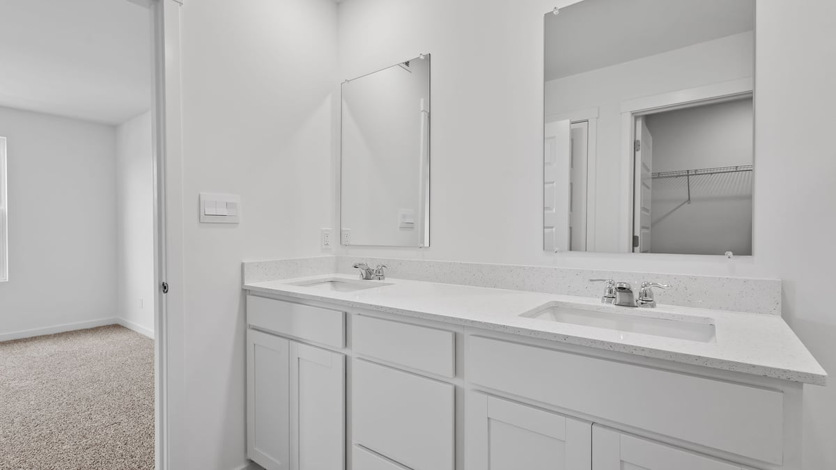 Bathroom with dual vanity sinks and white cabinets.