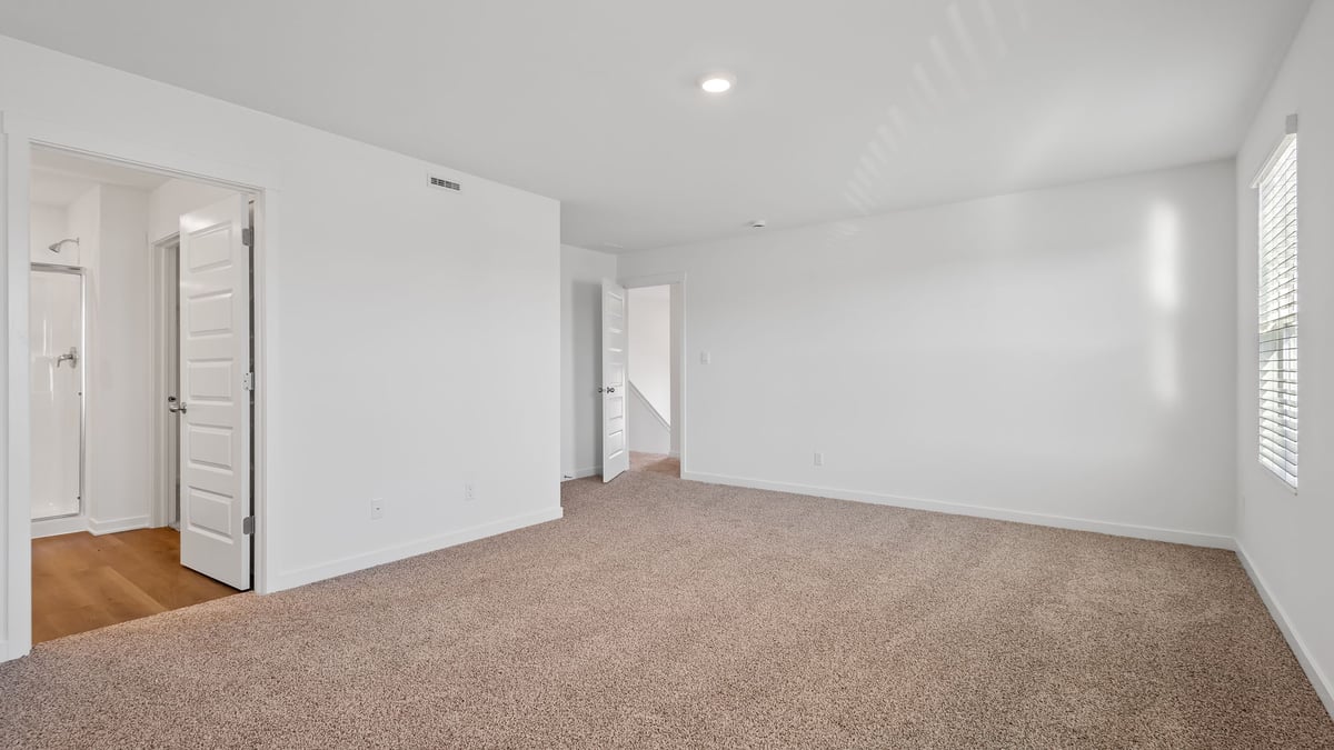 Primary bedroom with carpeted floors and a bathroom suite.