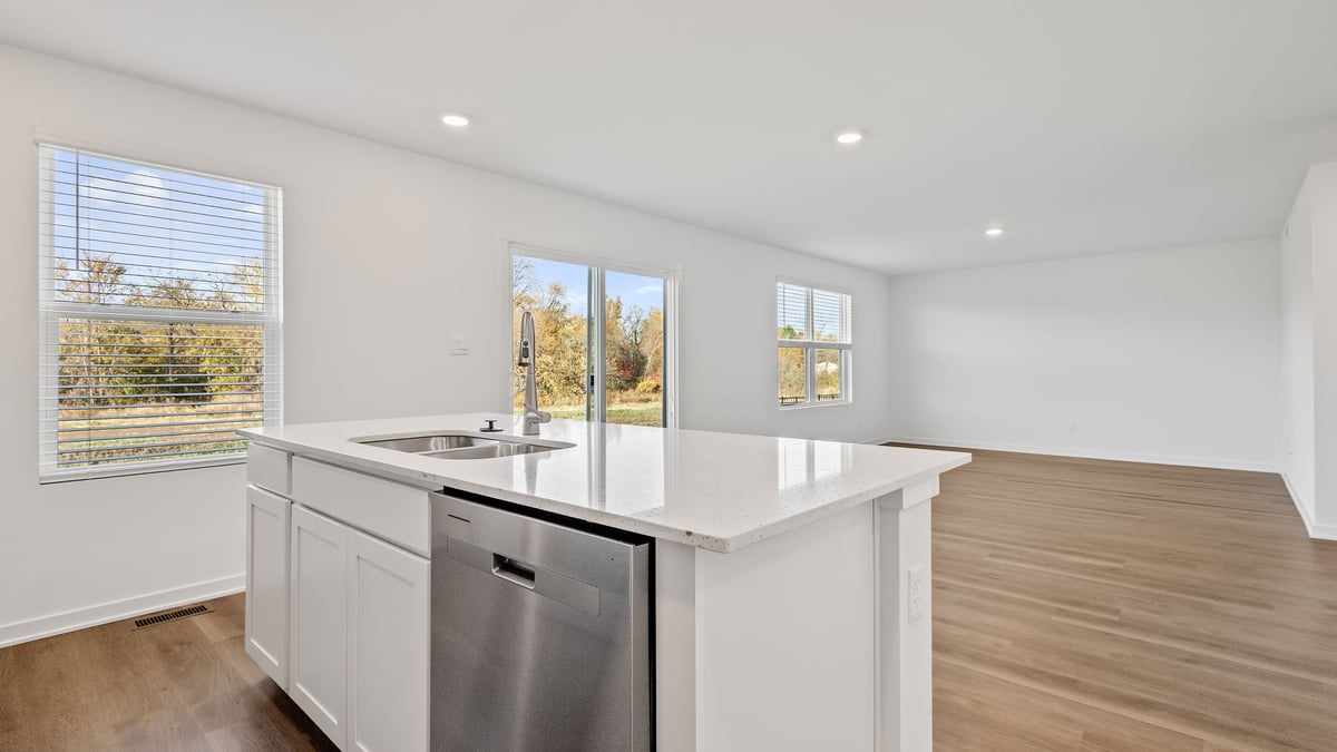 Kitchen island with quartz countertops and a side window and view of living area.