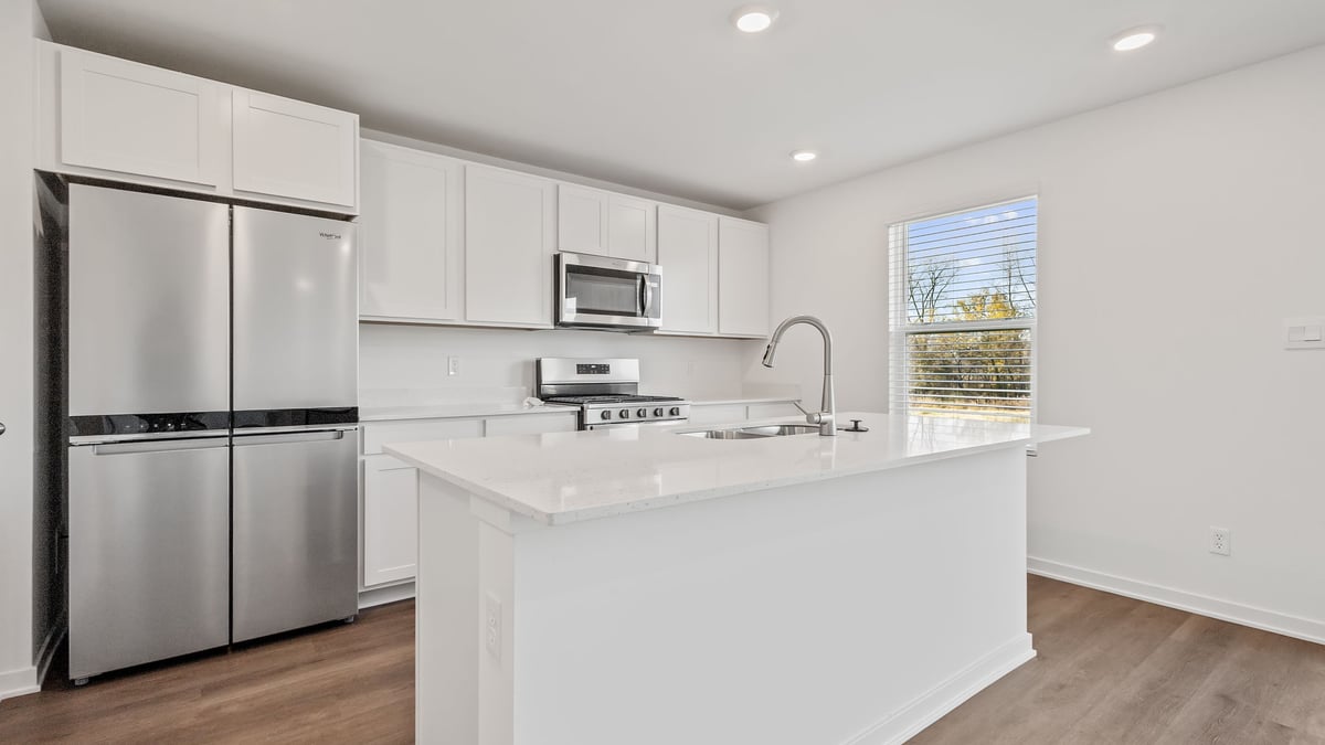 Kitchen with white cabinetry and a side window with hard wood floors.