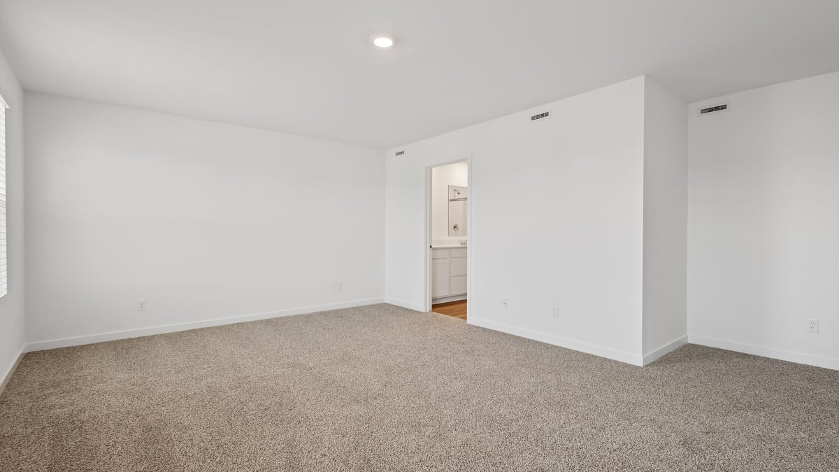 Primary bedroom with carpeted floors and a bathroom suite.