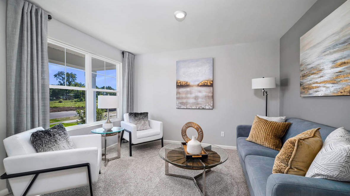 Front room staged as a seating area with carpet and a big window.