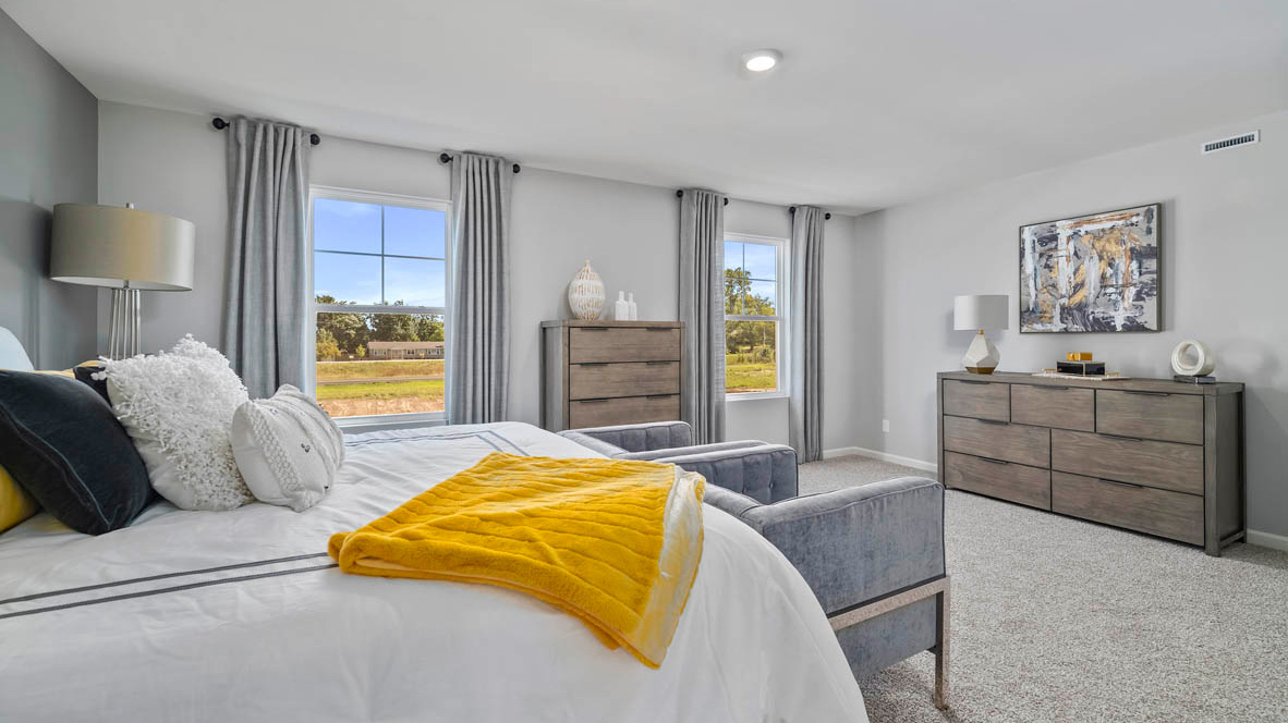 Primary bedroom with carpeted floors and two windows.
