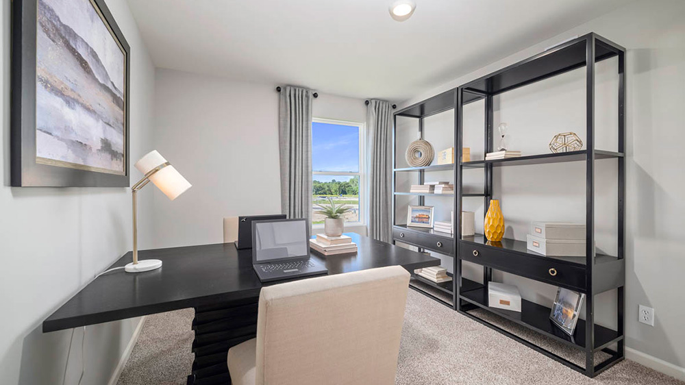 Staged office room with a side window and carpeted floors,