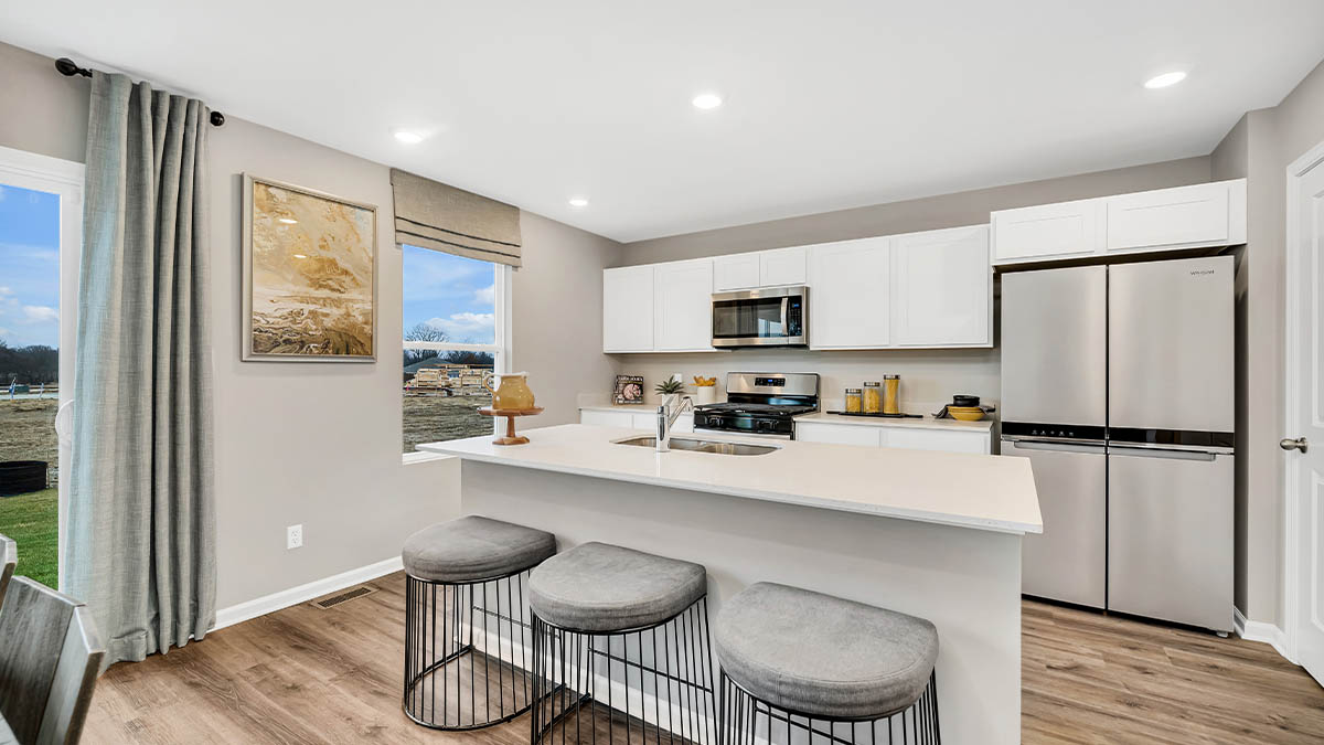 Kitchen with white cabinets with quartz countertops and a side window.