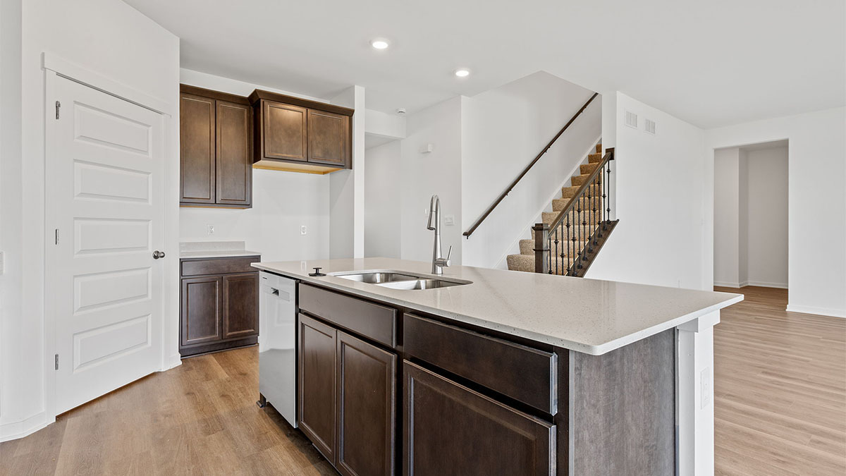 Kitchen with an island and a view of staircase.