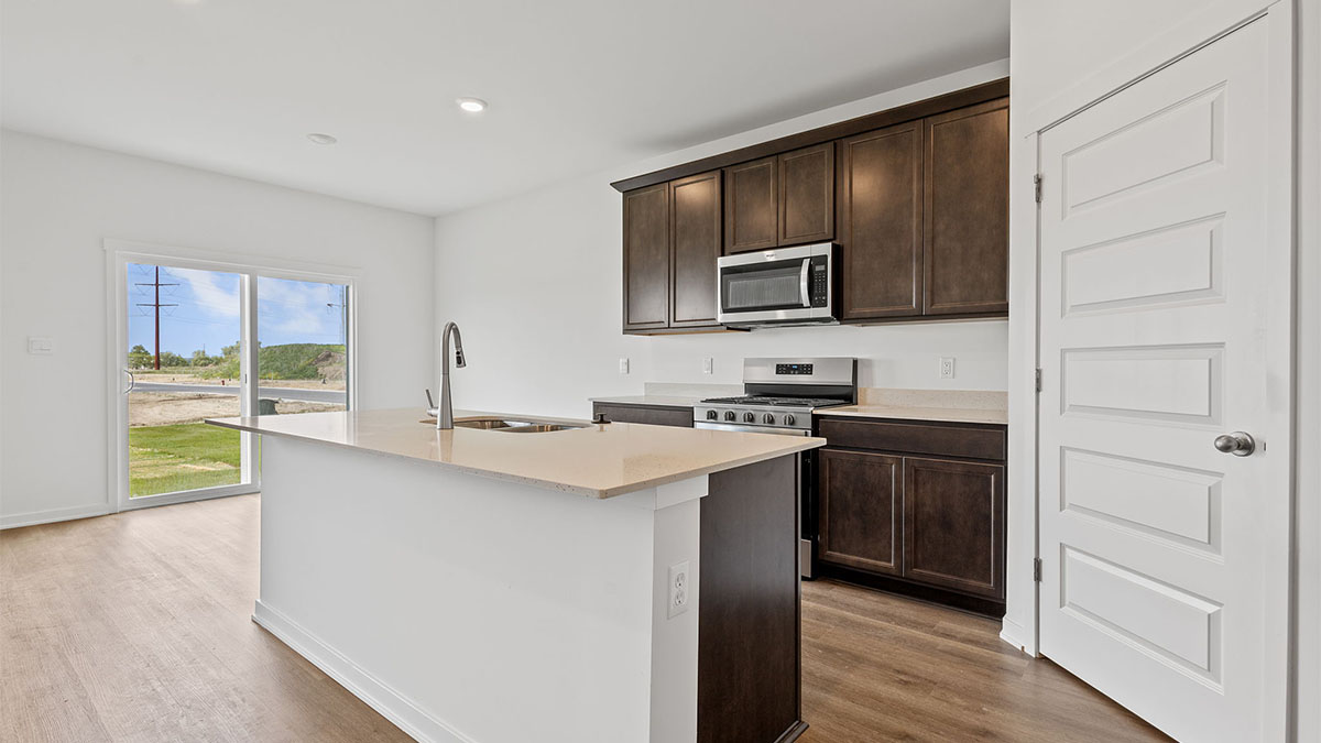 Kitchen with brown cabinets and a view of dining area with glass sliding door.