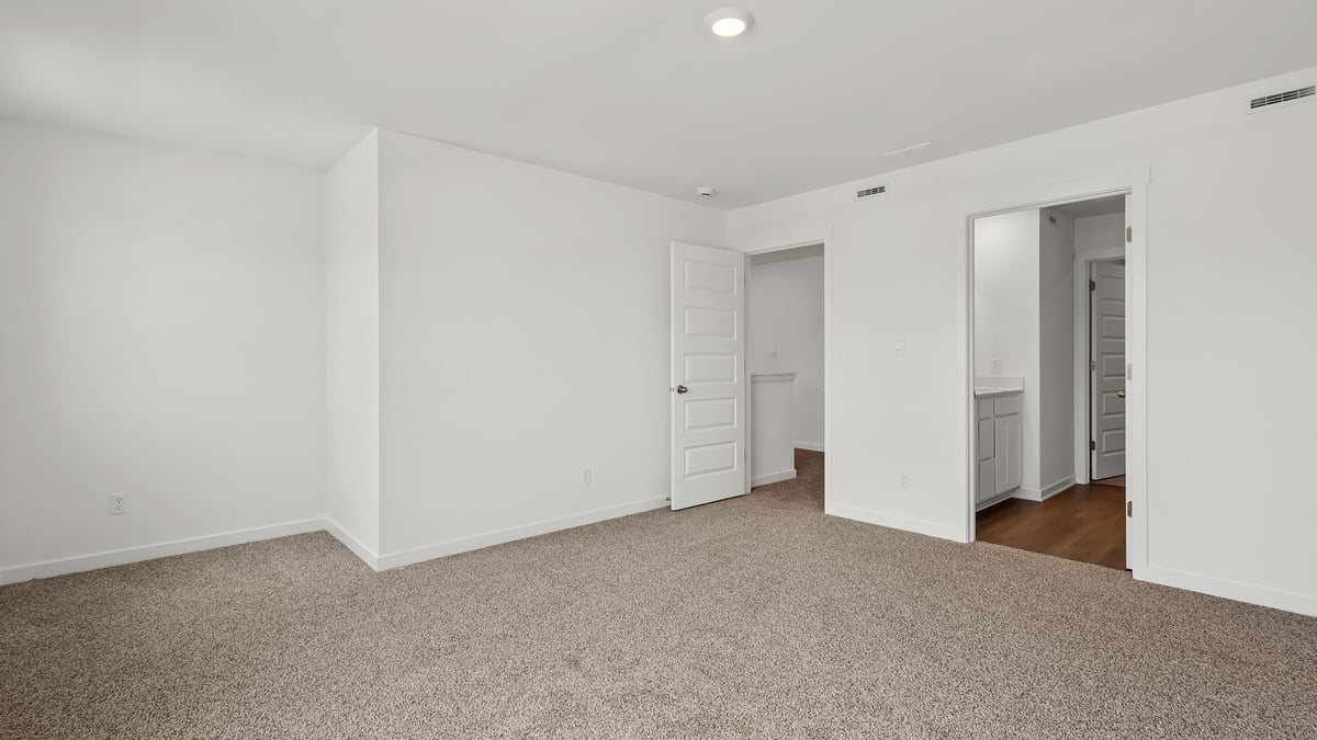 Bedroom with carpet and a bathroom.