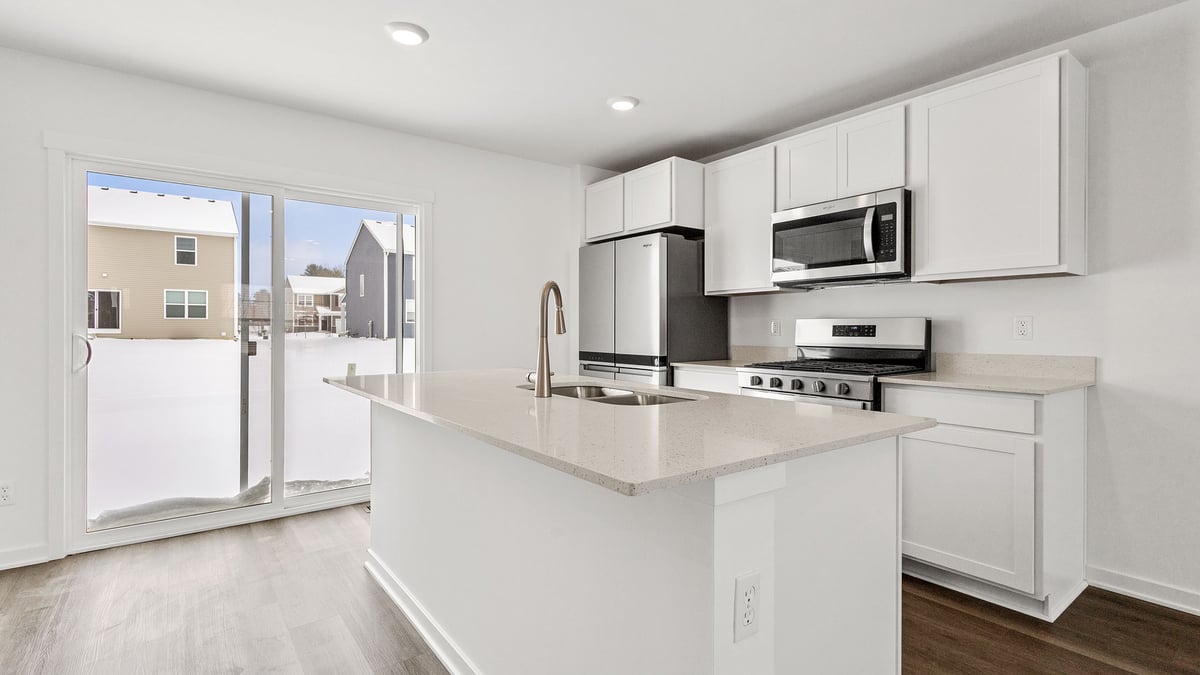 Kitchen with white cabinets with a glass sliding door with quartz countertops.