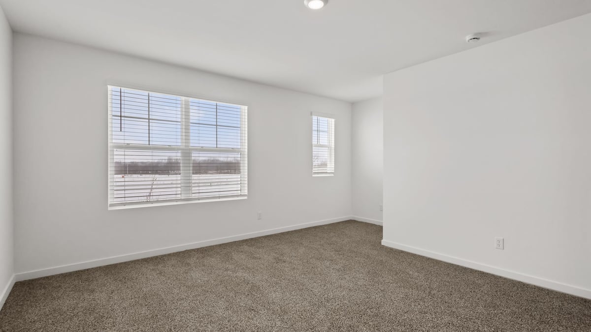 Primary bedroom with carpeted floors and a big window.