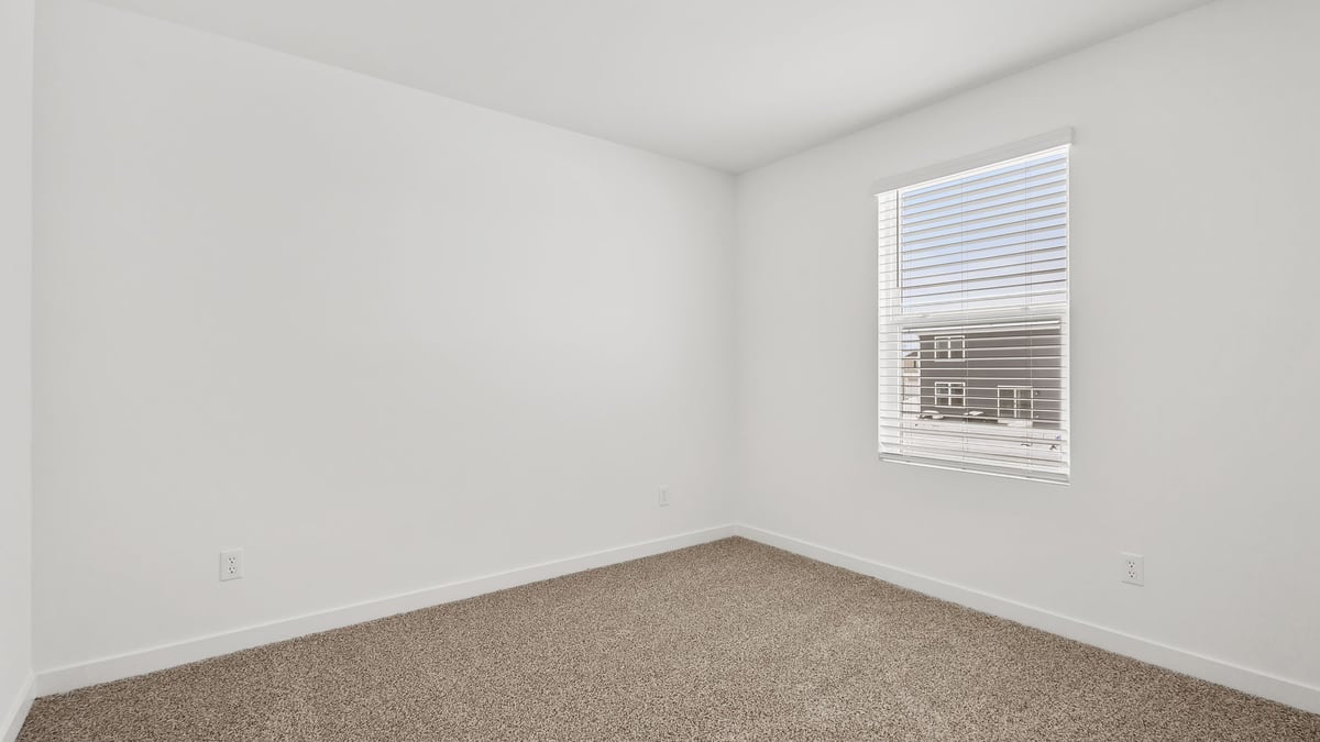 Bedroom with side window and carpeted floors.