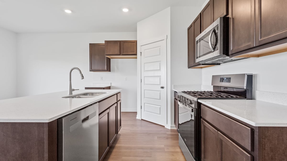 Kitchen with brown cabinets and view of island and microwave.