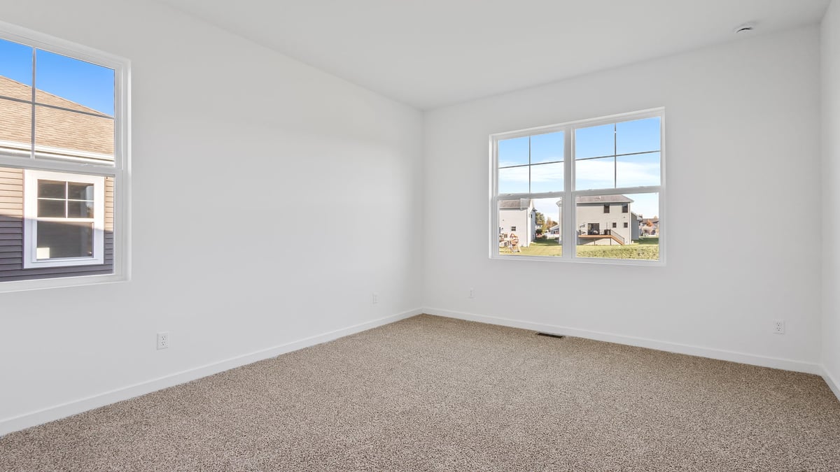Bedroom with carpet and two windows.