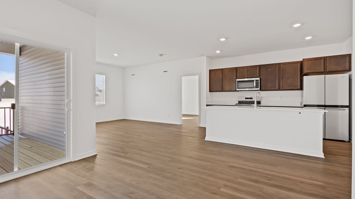 Kitchen with hard wood flooring and view of living room and living area.