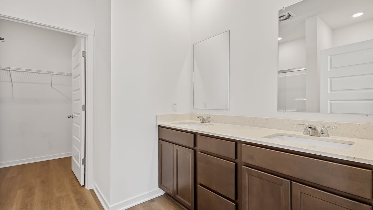 Bathroom with dual vanity sinks and a walk in closet.