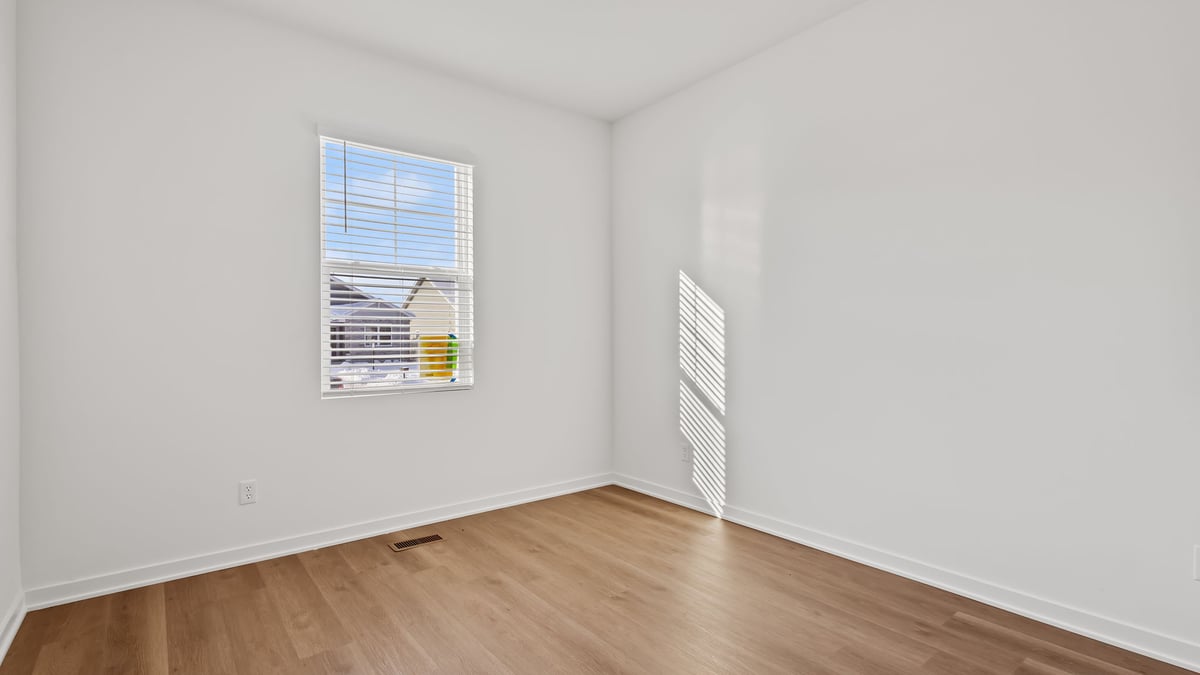 Bedroom with hard wood flooring and a window.