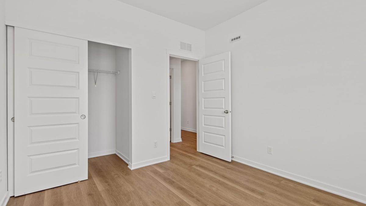 Bedroom with hard wood flooring and a closet.