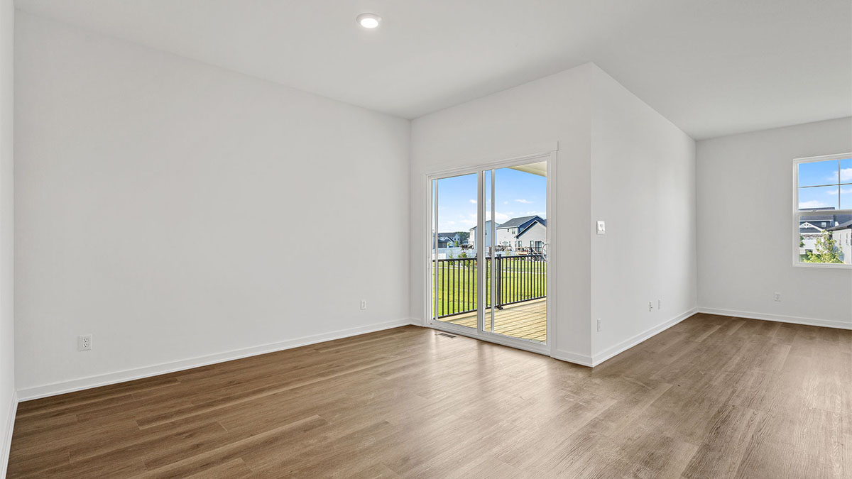 Living area with hard wood floors with glass sliding doors and windows.