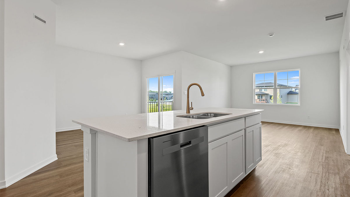 Kitchen island with white cabinets and a living area with hard wood floors.