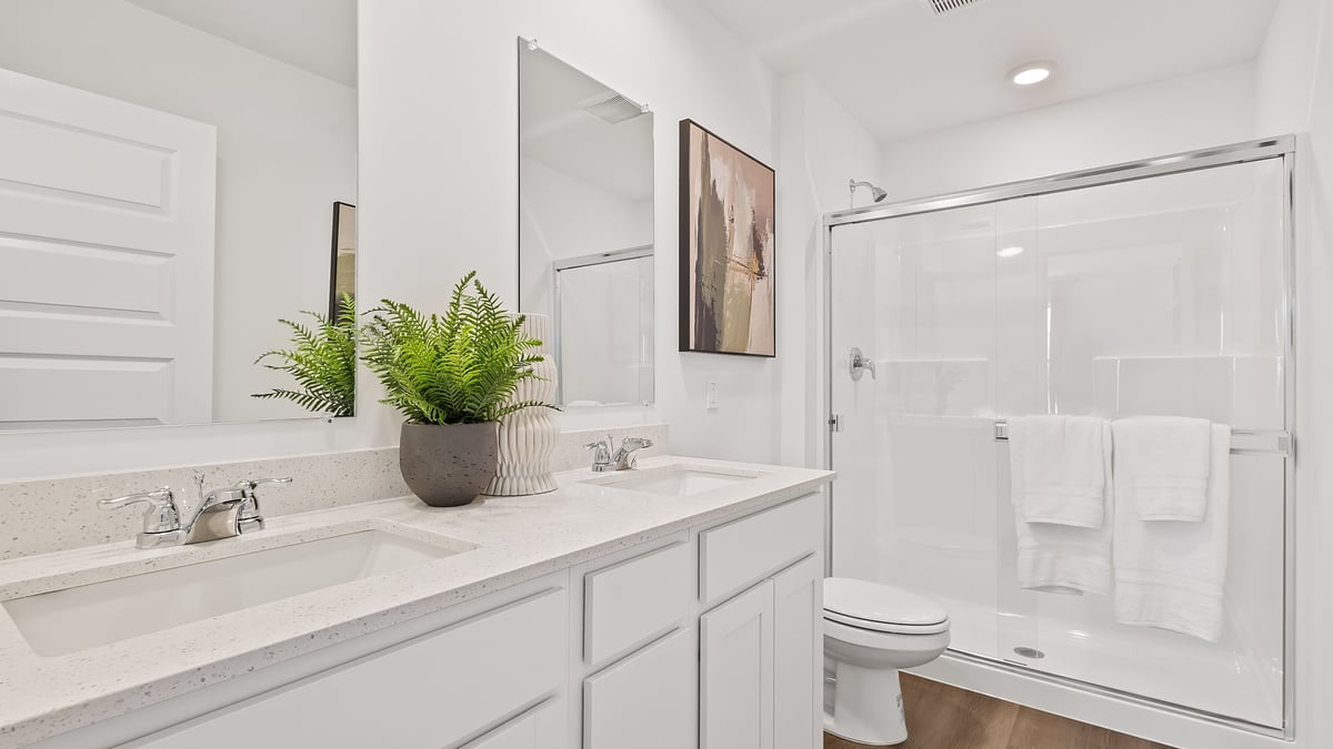 Primary bathroom with dual vanity sinks and a walk-in shower.
