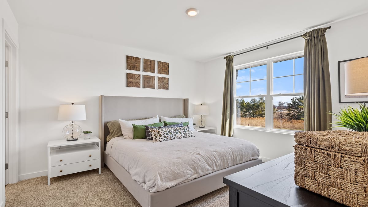 Primary bedroom with carpeted floors and a big window.