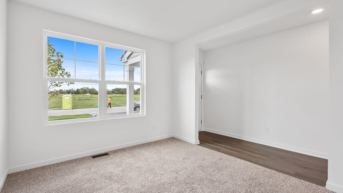 Front room with a big window and carpeted floors.