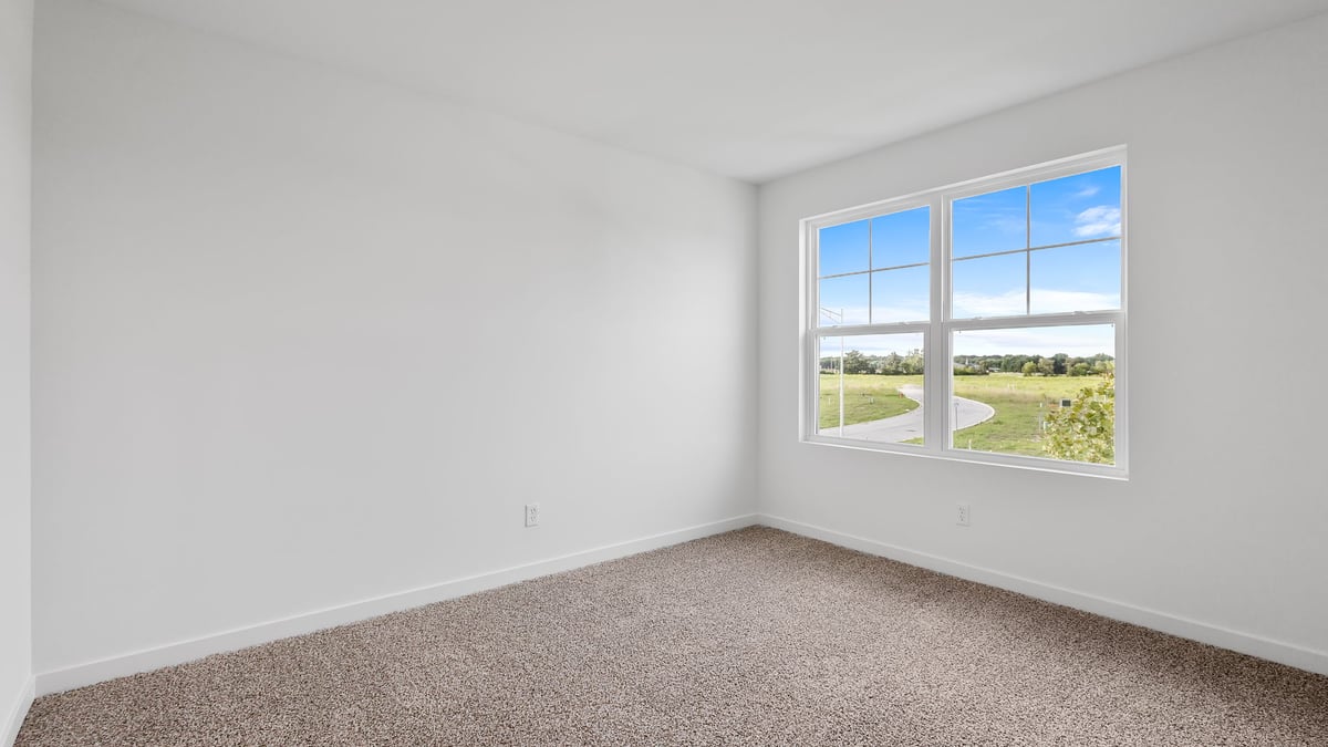 Bedroom with a big window and carpeted floors.