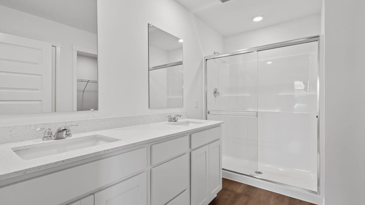 Primary bathroom with dual vanity sinks and a walk-in shower.