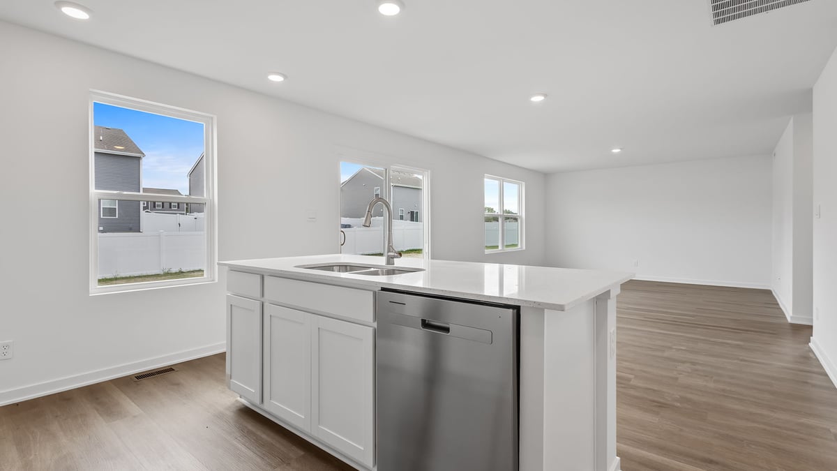 Kitchen island with quartz countertops and a side window and view of living room space.