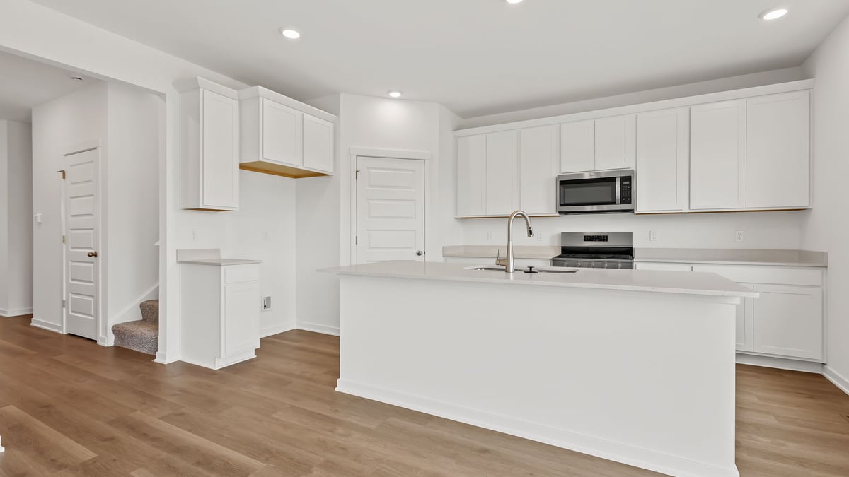 Kitchen with hard wood flooring and white cabinets.