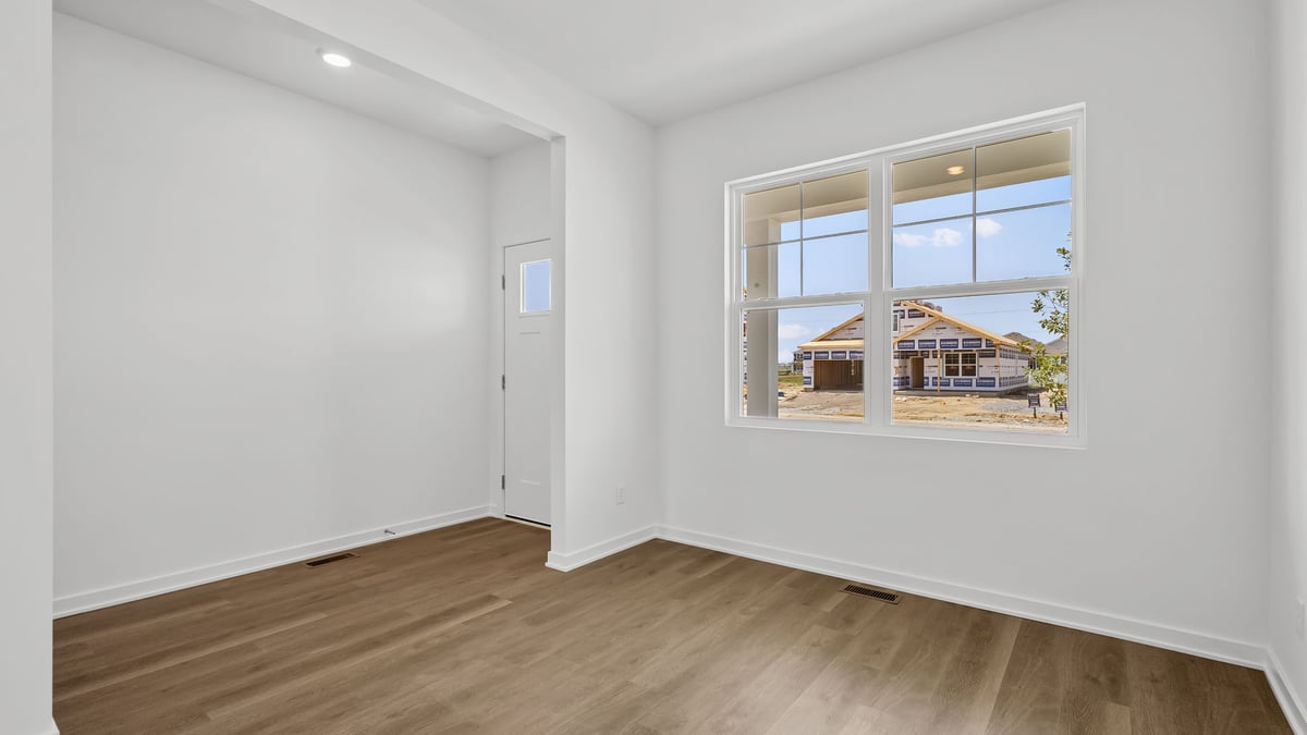 Front room with hard wood flooring and a big window.