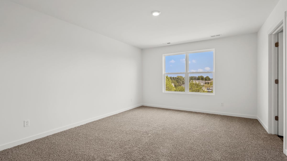 Primary bedroom with carpeted floors and a big window.