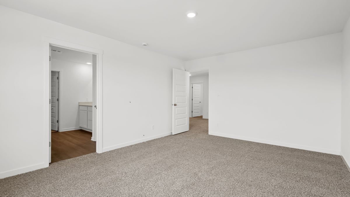 Primary bedroom with carpeted floors and a primary bathroom.