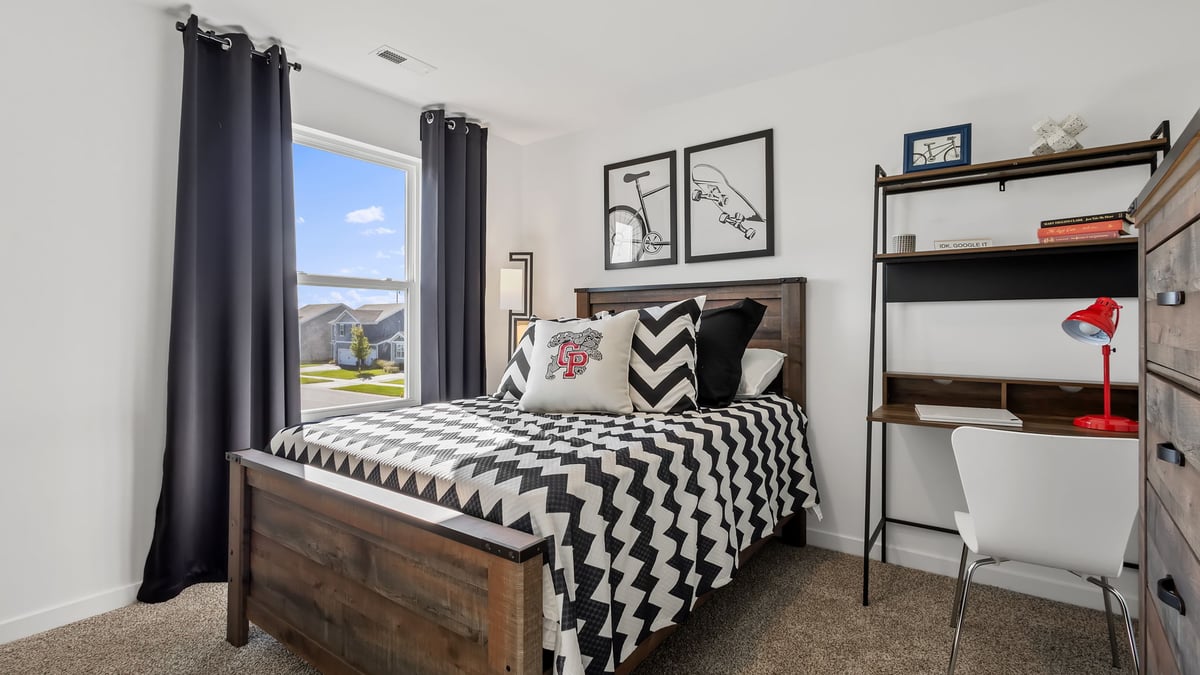 Bedroom staged as a kids room with a side window and carpet.