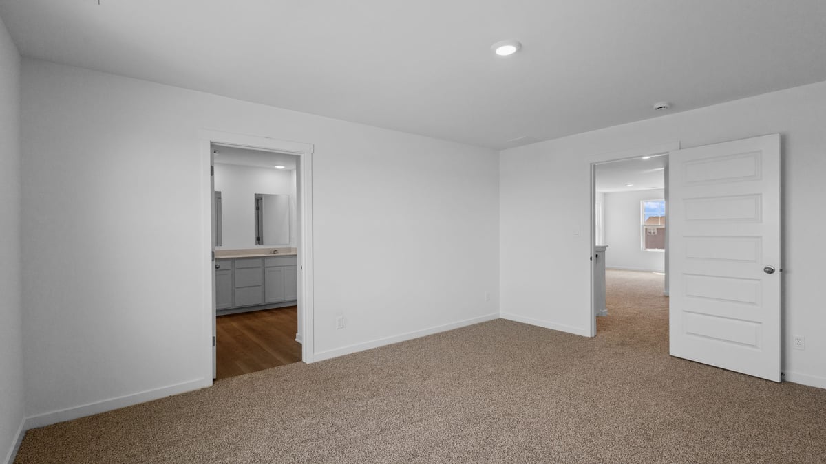 Primary bedroom with carpeted floors and a bathroom suite.