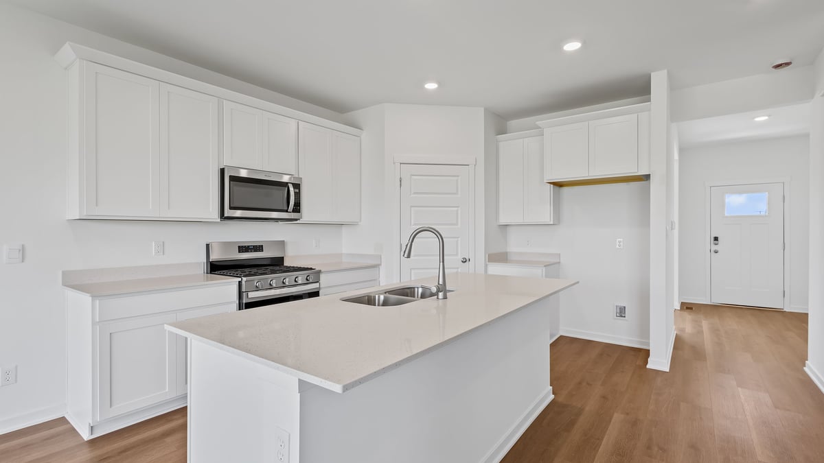 Kitchen with white cabinets and quartz countertops with hard wood flooring.