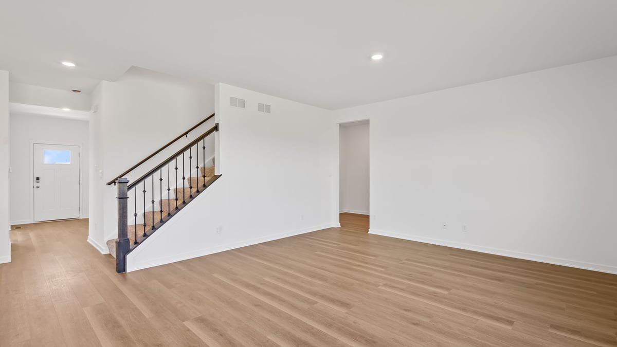 Living room area with hard wood flooring and open space.