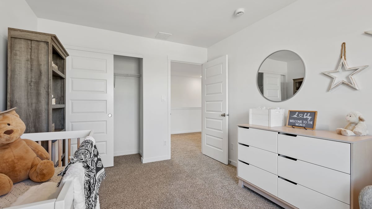Bedroom staged as a nursery with carpeted floors and a closet.