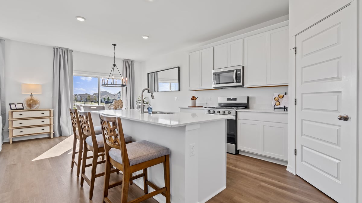 Kitchen with white cabinets and hard wood flooring with an open layout.