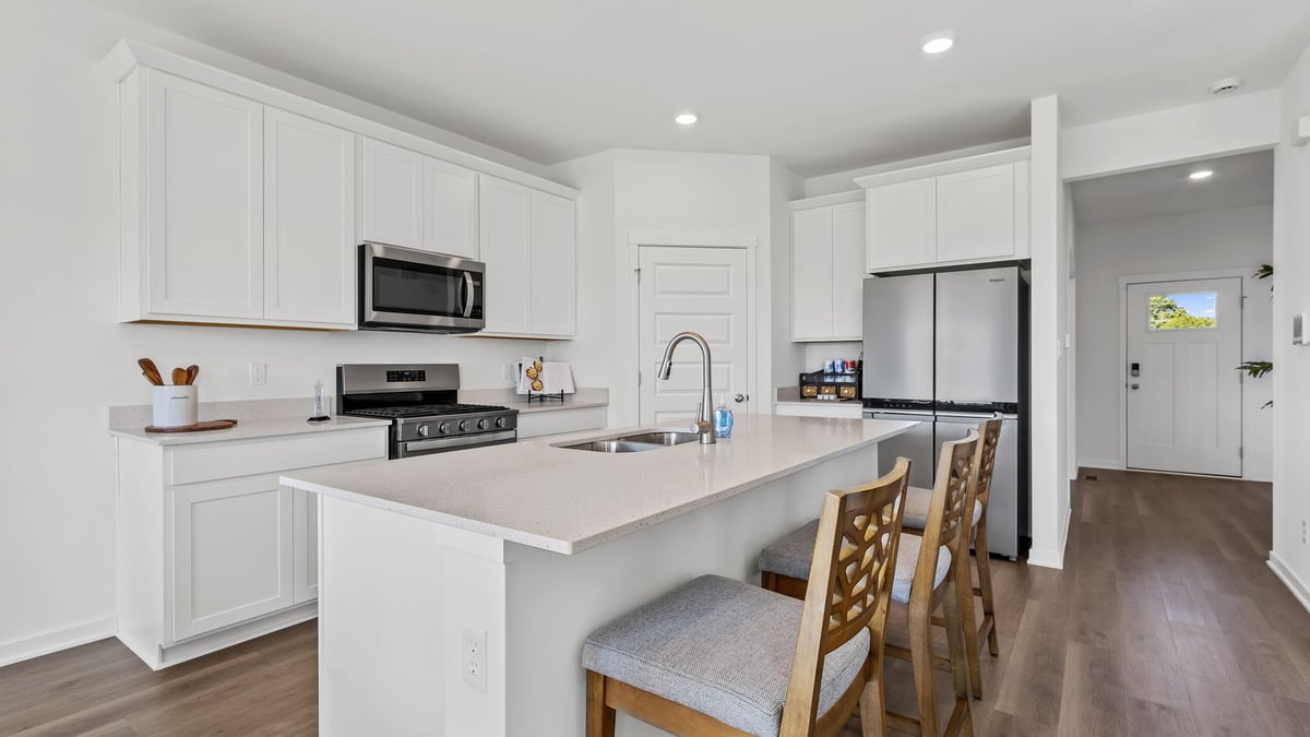 Kitchen with white cabinets and quartz countertops with hard wood flooring.