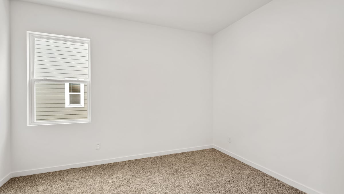Bedroom with one side window with carpeted floors.