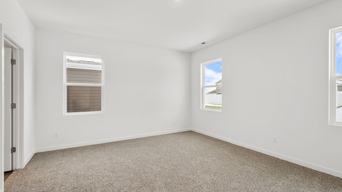 Primary bedroom with carpeted floors and windows.
