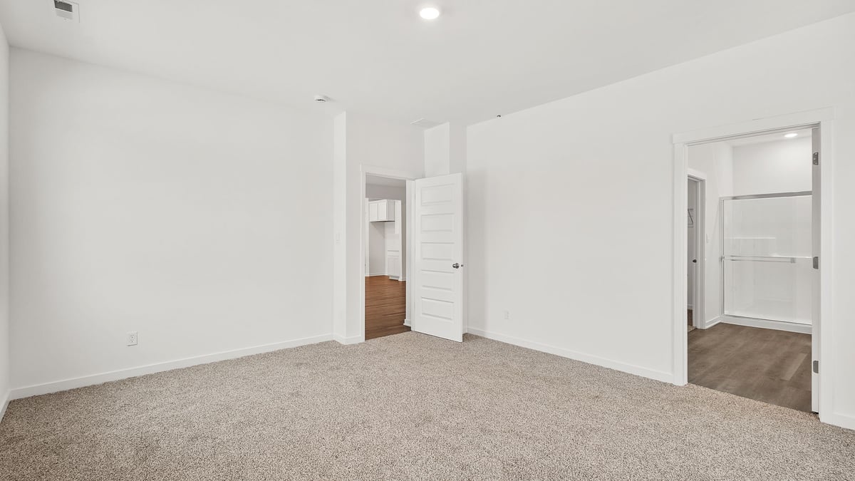 Primary bedroom with carpeted flroos and a bathroom suite.