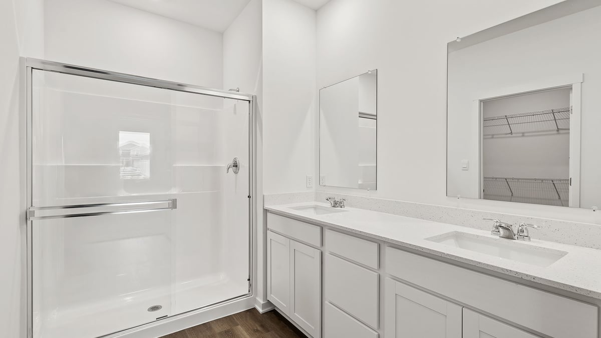 Primary bathroom suite with a walk in shower and dual vanity sinks.