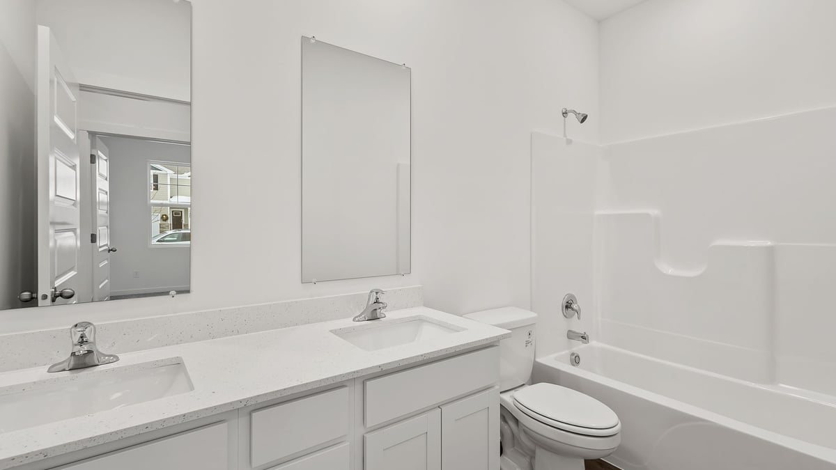 Dual vanity sink with quartz countertops and a shower.