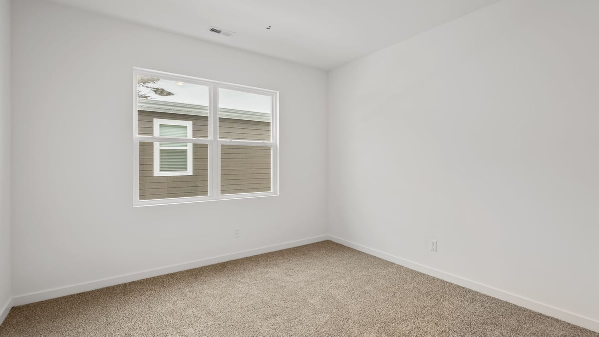 Bedroom with carpeted floors and a big window.