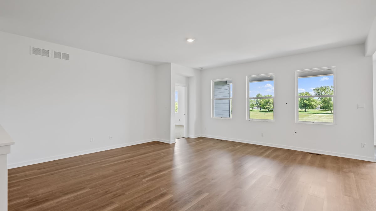 Living room with windows and hard wood flooring and an open layout.