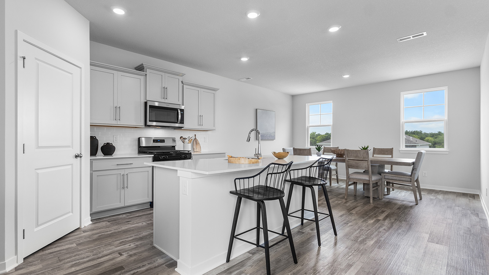 Kitchen and island with white cabinets and stainless steel appliances. New Homes in Kansas City, Missouri