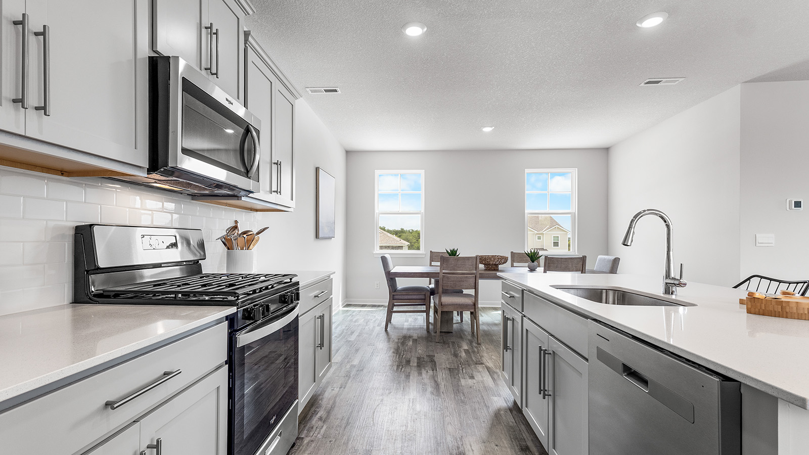 Kitchen and island with white cabinets and stainless steel appliances. New Homes in Kansas City, Missouri