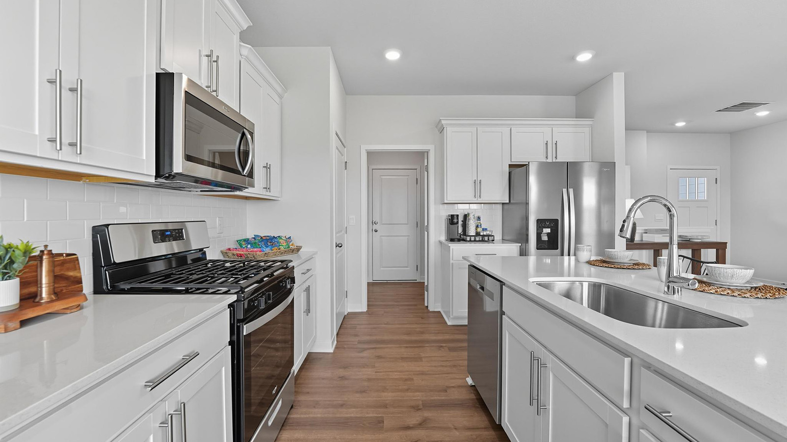 Open-concept kitchen with white counters and cabinets, and stainless steel appliances